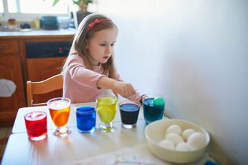 Wall Mural - Adorable preschooler girl dyeing Easter eggs at home