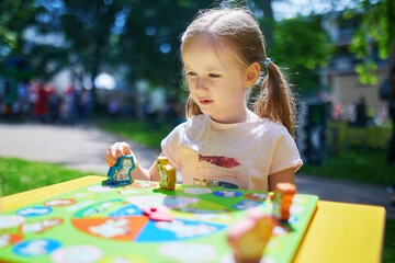 Wall Mural - preschooler girl playing board game outdoors