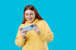 © mdyn - Close up portrait of a Happy 30s woman playing games with a smart phone isolated on a blue background