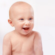 © T. Rose/peopleimages.com - Young, happy and face of baby on a white background for child development, laugh and growth. Curious, facial expression and closeup of isolated newborn for childhood, wellness and adorable in studio