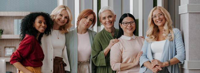 Wall Mural - Group of mature businesswomen bonding and smiling while standing in the office together