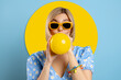 © gstockstudio - Playful young woman blowing up a balloon while standing against blue background