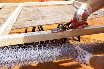 Worker uses scissors for metal to cut metal mesh