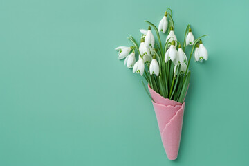 Sticker - large white Snowdrop flower arrangement delicately placed inside a pink ice cream cone. The arrangement stands out against a bright green background. for various design projects, spring concepts