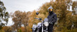 © velimir - motorcyclist in a motorcycle jacket and tinted helmet with a classic motorcycle in nature. Stylish biker