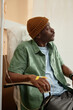 © Seventyfour - Vertical side view portrait of African American man wearing beanie hat while receiving IV treatment in clinic