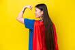 Young Chinese woman isolated on yellow background in superhero costume and doing strong gesture