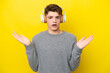 Teenager Russian man isolated on yellow background surprised and listening music