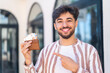 © luismolinero - Handsome Arab man at outdoors holding wallet with money and pointing it