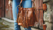 A boho leather bucket bag with fringe accents and a drawstring closure, adding a bohemian flair to any outfit.