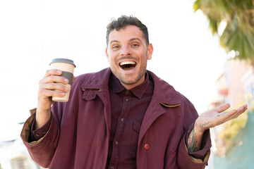 Wall Mural - Young caucasian man holding a take away coffee at outdoors with shocked facial expression