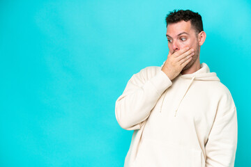 Poster - Young caucasian handsome man isolated on blue background doing surprise gesture while looking to the side