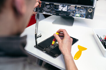 Hands fixing a tablet with tools