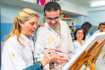 Instructor helping a disabled man during painting class