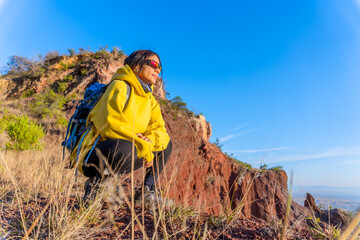 woman in the mountains, with backpack and a yellow jacket, motivated by exploring new places. Concept: trekking, freedom, travel, exploration, motivation