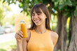 © luismolinero - Young woman holding an orange juice at outdoors with happy expression