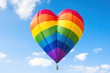 Fototapeta Sport - Colorful hot air balloon in the shape of a heart on blue sky background. LGBT Concept with Copy Space. Pride Month Concept.
