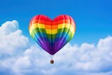 Fototapeta Sport - Colorful hot air balloon in the shape of a heart flying in the blue sky. LGBT Concept with Copy Space. Pride Month Concept. LGBT Concept with Copy Space. Pride Month Concept.