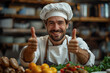 Portrait of a smiling male chef showing thumbs up in the kitchen with blurred vegetables on foreground