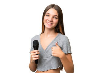 Poster - Teenager singer girl picking up a microphone over isolated background giving a thumbs up gesture