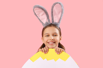 Wall Mural - Cute little girl with Easter bunny ears and big paper egg on pink background