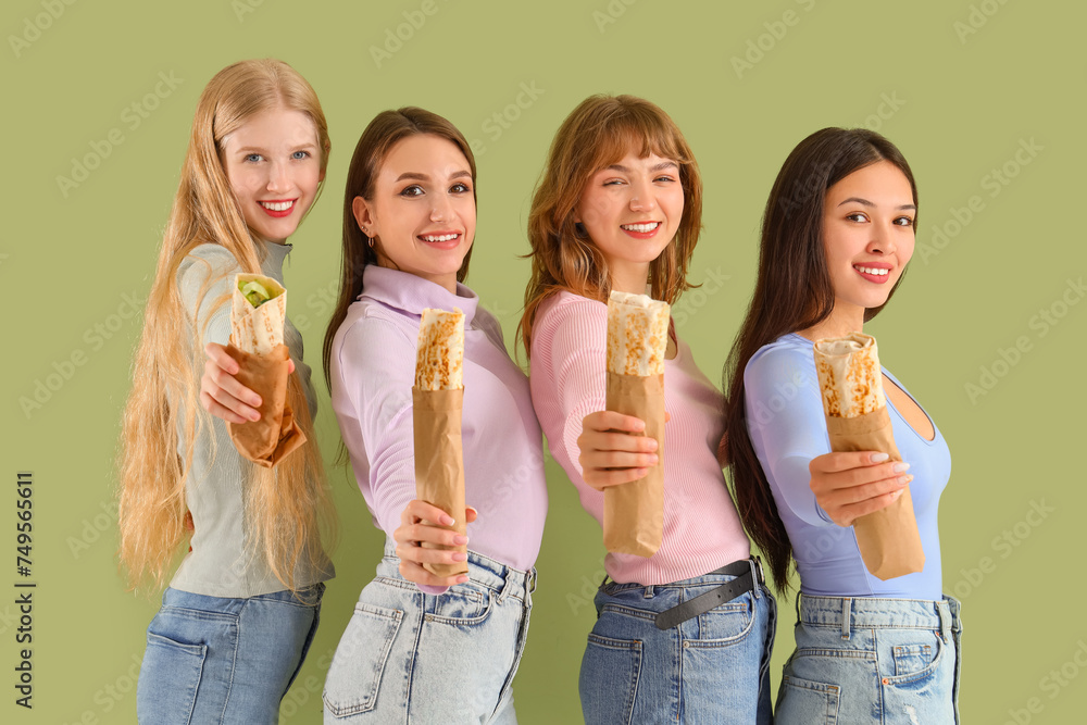 Young women with doner kebabs on green background