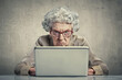© wernerimages - angry old lady sitting behind a laptop