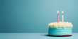 Birthday banner with two cake with burning candles in front of blue studio background