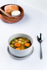 Canvas Print - Fresh chicken broth with meatballs, noodles, potato gnocchi and microgreens.