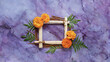 square wooden frame on purple marble surface copy space,with marigold flowers symbol of positive emotion,joy,good luck and prosperity.