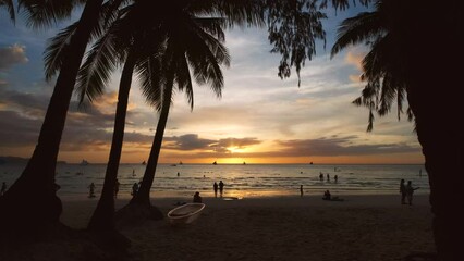 Wall Mural - Silhouetted people and palms near sea. Sunset at tropical White beach, Boracay island, Philippines, slow motion 4k