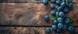 A collection of ripe blueberries arranged neatly on a rustic wooden table. The blueberries are fresh and vibrant, showcasing their natural colors against the warm wood backdrop.