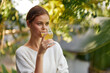 © SHOTPRIME STUDIO - Happy Woman Enjoying a Refreshing Kombucha Drink in the Sunlight, Surrounded by Nature and Holding a Glass of Antioxidantrich Detoxing Beverage