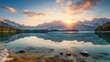 A breathtaking sunrise over a serene lake, reflecting majestic snow-capped mountains and lush green forest. Ideal for nature-themed content, high-resolution landscape photography, and wallpapers