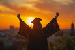 Silhouette of graduate wearing black academic gown and graduation cap with yellow tassel, right hand raised enthusiastically as a sign of success.