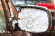 Snowing covers the side mirror of a car in winter in Chicago.