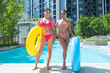 © Washburn - Female friends in bikinis playing with colorful rubber rings by the pool