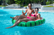 © Washburn - Female friends in bikinis play with watermelon-patterned rubber rings by the pool.