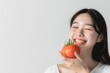 © Daniil - Asian woman holding a tomato. Follows a diet. Isolated background