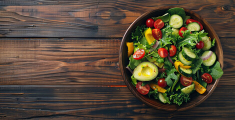 Top view of a colorful salad bowl filled with fresh mixed greens, cherry tomatoes, cucumbers, bell peppers, and avocado slices, drizzled with balsamic vinaigrette, on a wooden table wth copyspace.