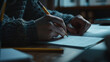 © VK Studio - Low-lit study moment captures the dedication of pen on paper writing.