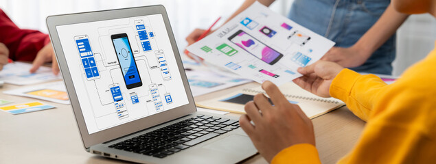 Panorama banner of startup UX developer or company employee design user interface or UI prototype for mobile application or website software with software display on laptop monitor in office. Synergic