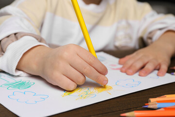 Wall Mural - Little boy drawing with pencil at wooden table, closeup. Child`s art