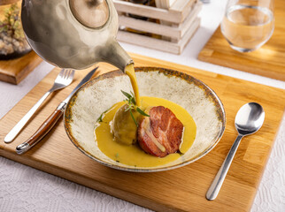 Canvas Print - Waiter pours cream soup into a baked potato