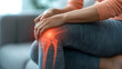 Close-up of an adult's knee with glowing pain points, sitting on a couch, indicating joint discomfort in a home setting. joint inflammation, bone fracture, osteoarthritis, leg injury