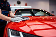 © KidSpace - Auto service staff cleaning a red car with a wipe.