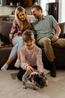 © BGStock72 - Family bonding time with playful french bulldog pup in cozy living room