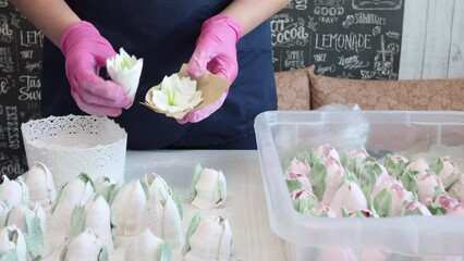 Wall Mural - A woman demonstrates lily flowers made of marshmallows. There are zephyr tulips on the table.