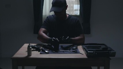 Wall Mural - Slow motion image of a man sitting alone in a room. He would disassemble and clean a 9 mm semi-automatic pistol. assembling the gun. military ammunition. weapon care.