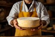 Cheese expert connoisseur holds in hands crafted cheese wheel